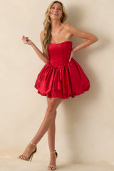 A full front view of the red strapless mini dress with a corset top and v-waistline.