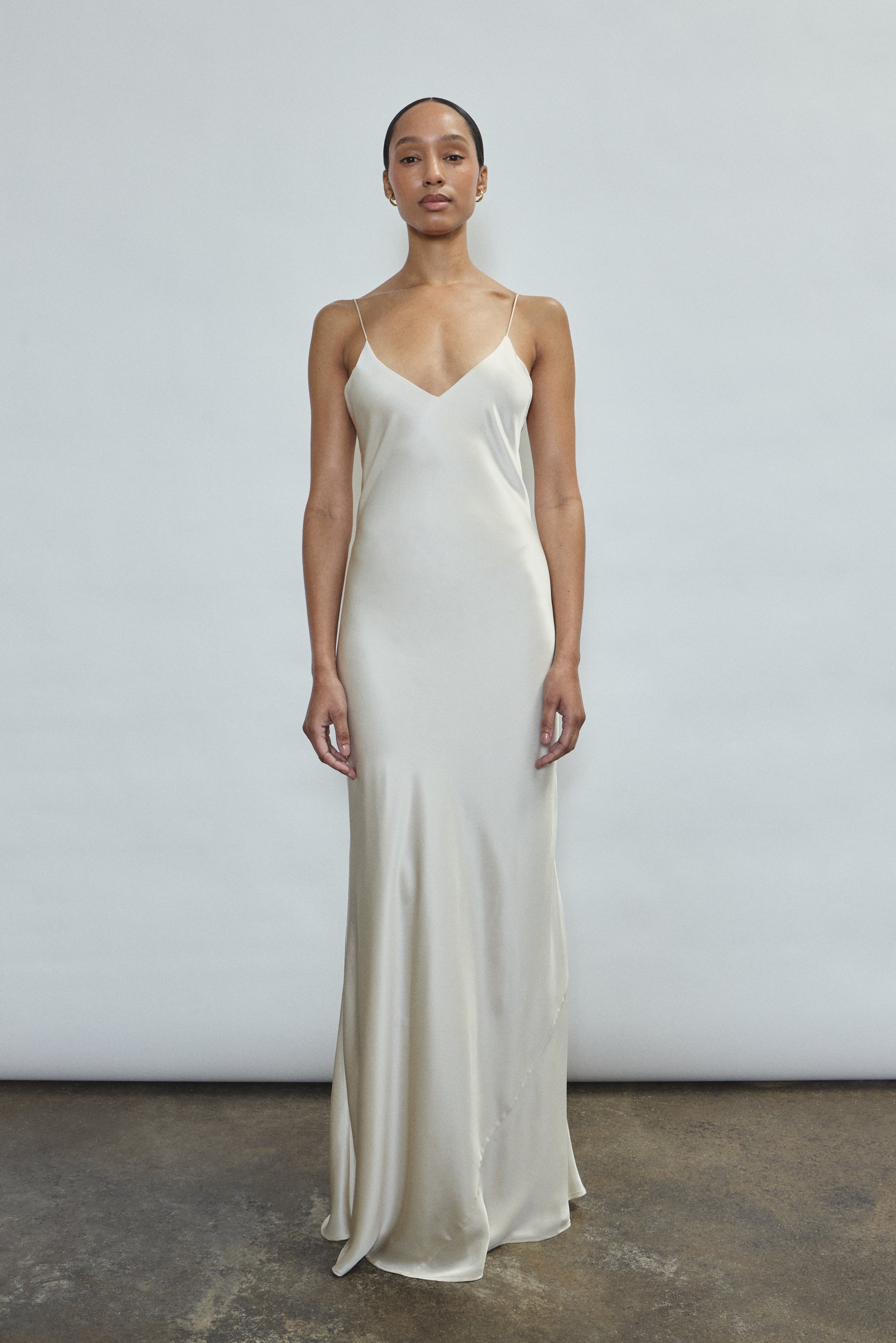 Front view of a bride wearing the ivory sueded silk charmeuse Kamperett Caroline Slip Dress, a maxi-length bias-cut bridal slip with V-neck and corded straps.