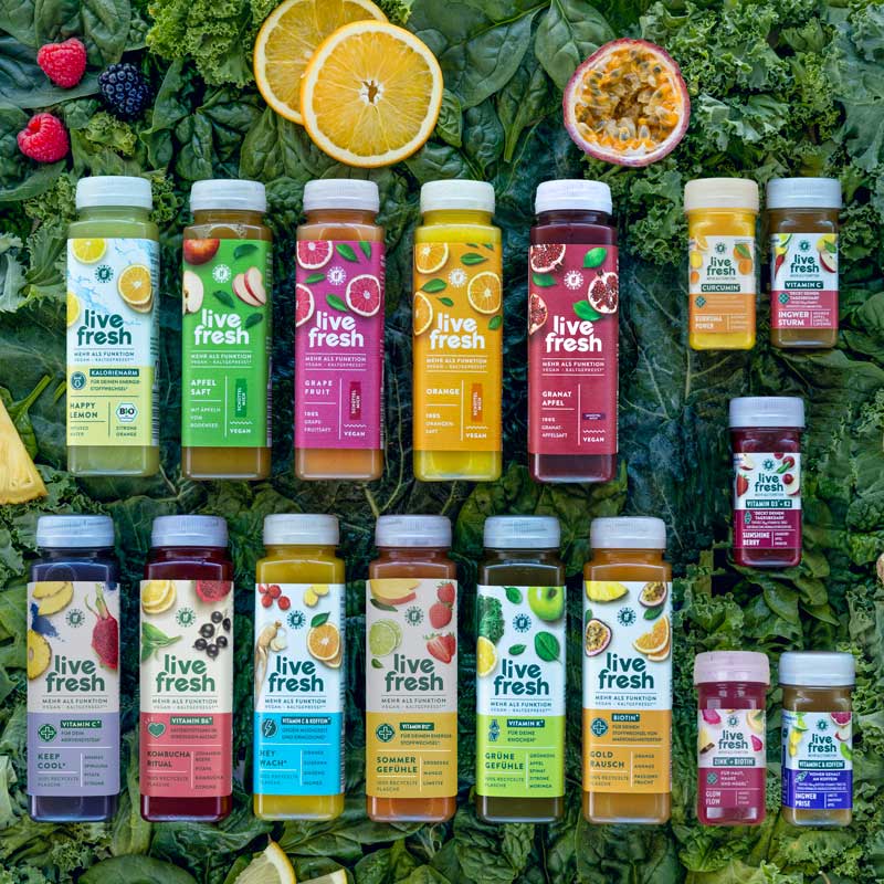Sechzehn verschiedene LiveFresh kaltgepresste Säfte und Shots auf grünem Hintergrund – Großes Probierpaket Alle Säfte und Shots von LiveFresh