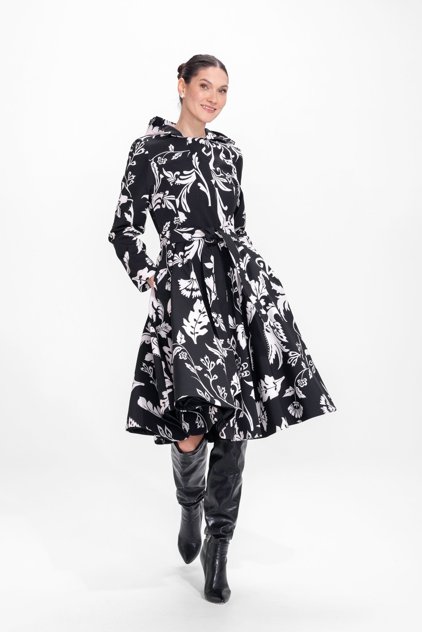 Model twirling in black with white floral print coat with flared skirt and tailored waist