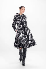 Model twirling in black with white floral print coat with flared skirt and tailored waist