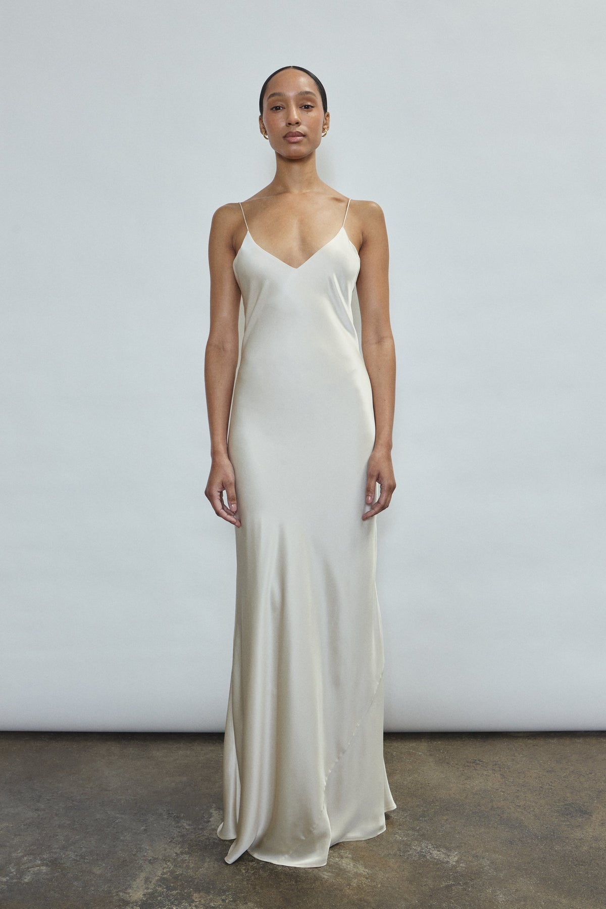 Front view of a bride wearing the ivory sueded silk charmeuse Kamperett Caroline Slip Dress, a maxi-length bias-cut bridal slip with V-neck and corded straps.