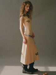Woman wearing a beige dress with black patterns on a plain background