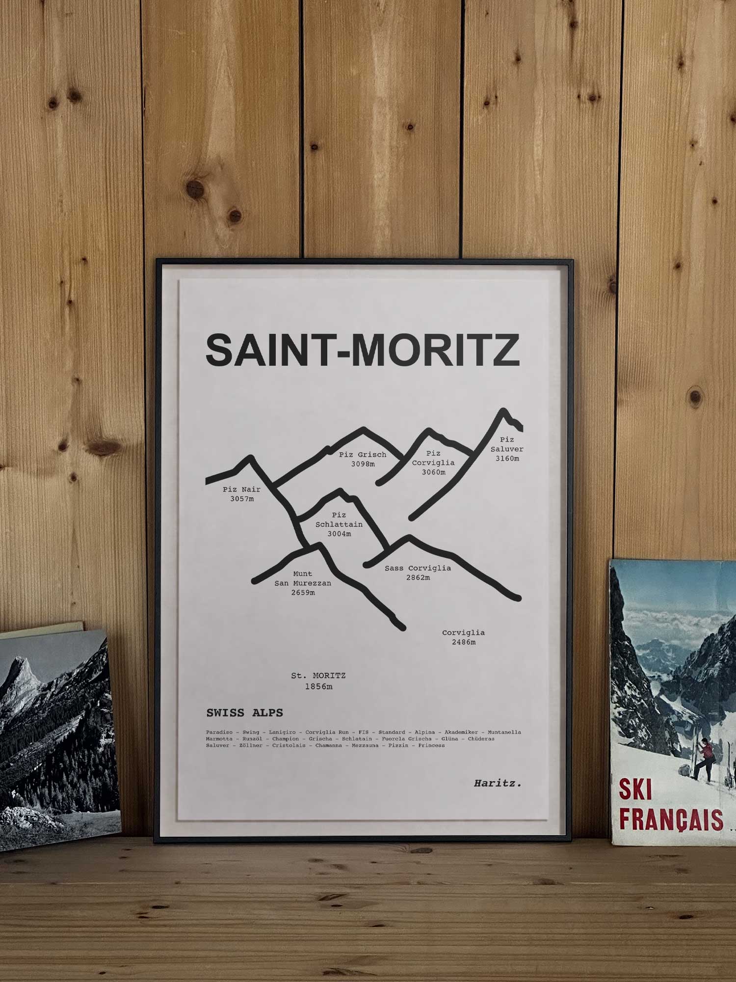 Affiche Saint-Moritz représentant le tracé topographique des sommets, encadrée avec un cadre noir et posée sur une étagère en bois dans une décoration chalet montagne, création Haritz.