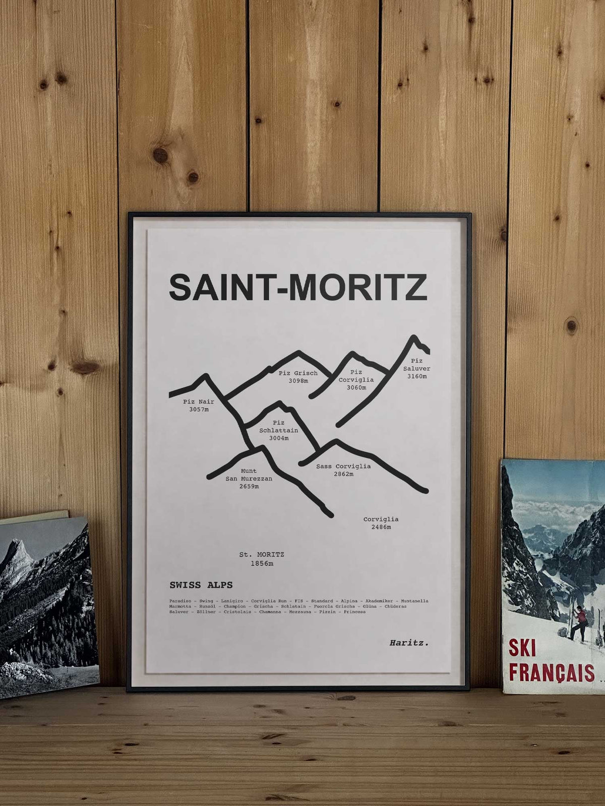 Affiche Saint-Moritz représentant le tracé topographique des sommets, encadrée avec un cadre noir et posée sur une étagère en bois dans une décoration chalet montagne, création Haritz.
